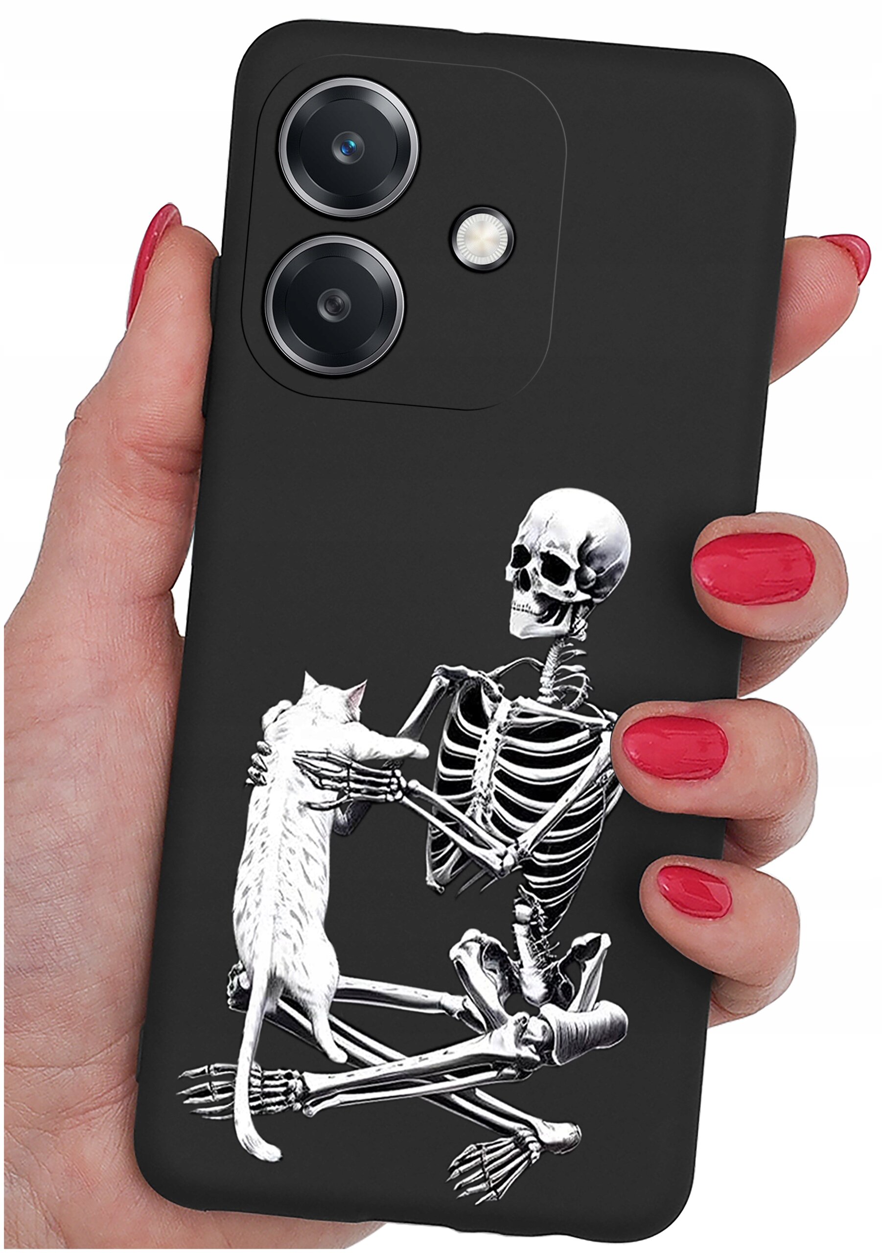 Czarne etui na telefon z nadrukiem szkieletu trzymającego kota. Etui jest trzymane w dłoni z pomalowanymi na czerwono paznokciami.