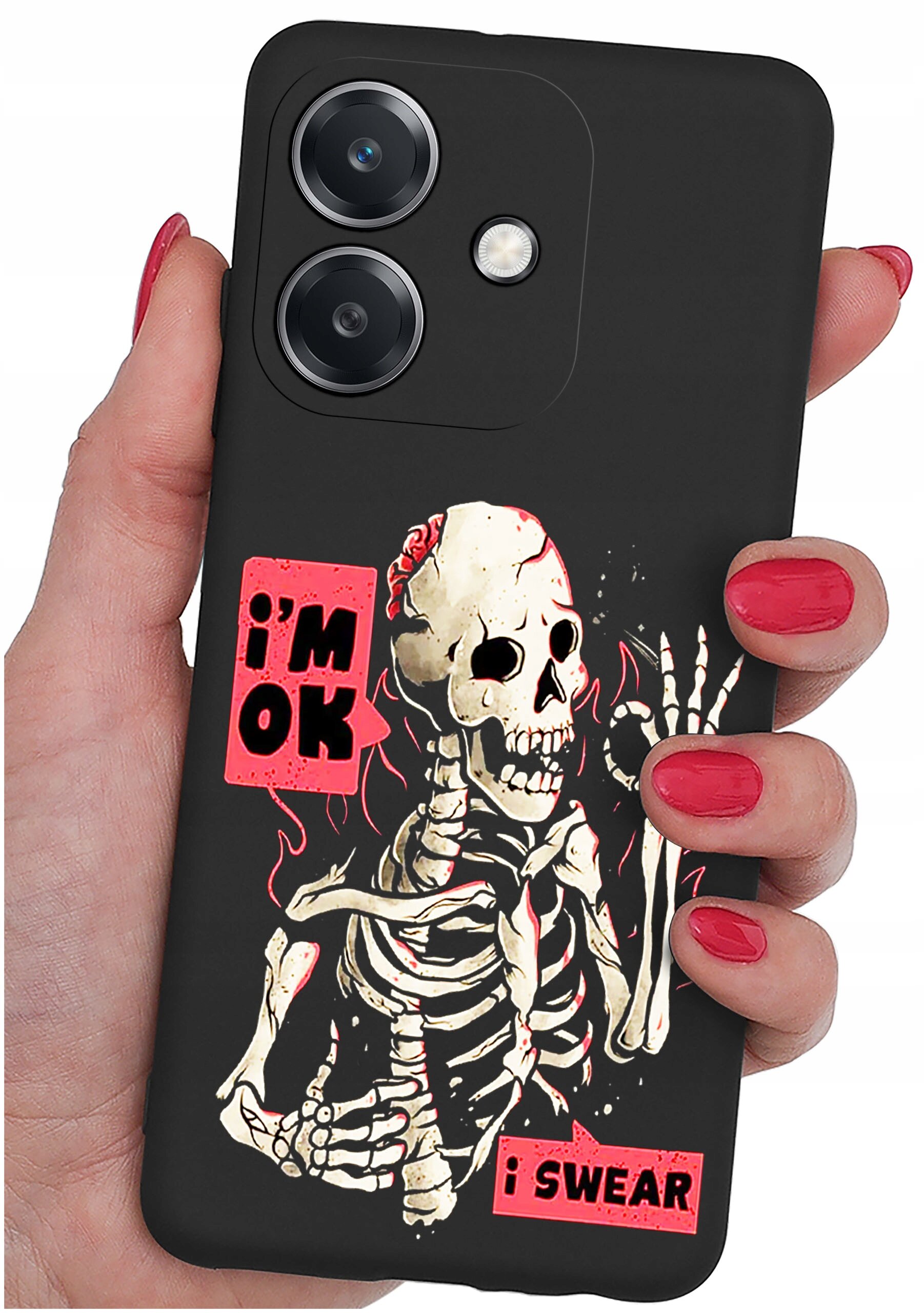 Czarna obudowa telefonu z nadrukiem szkieletu i napisami \'i\'m OK\' oraz \'i SWEAR\'. Obudowa jest trzymana w dłoni z pomalowanymi na czerwono paznokciami.