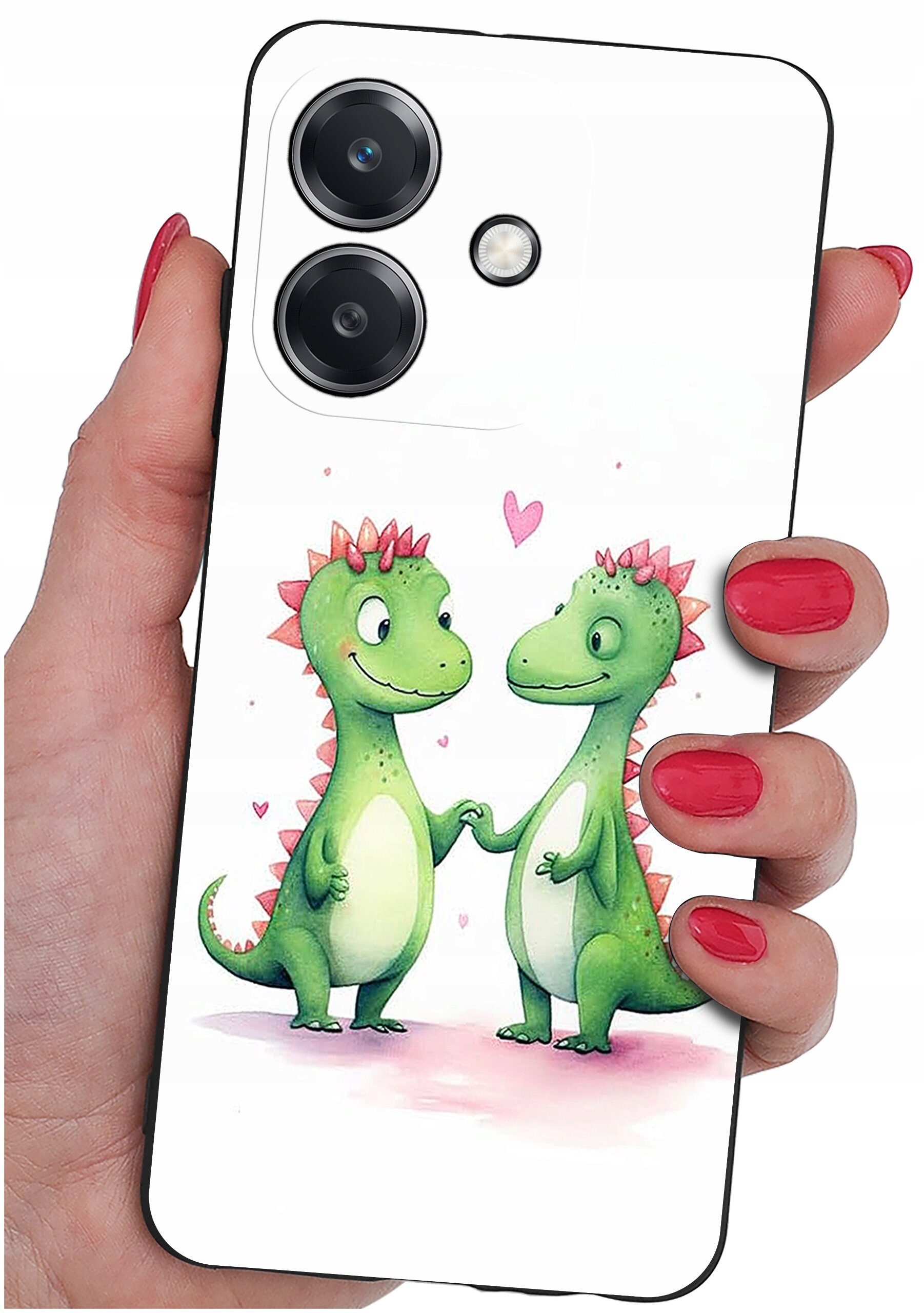 Etui na telefon z motywem dwóch zielonych dinozaurów trzymających się za ręce, otoczonych różowymi serduszkami. Etui jest trzymane w dłoni z pomalowanymi na czerwono paznokciami.