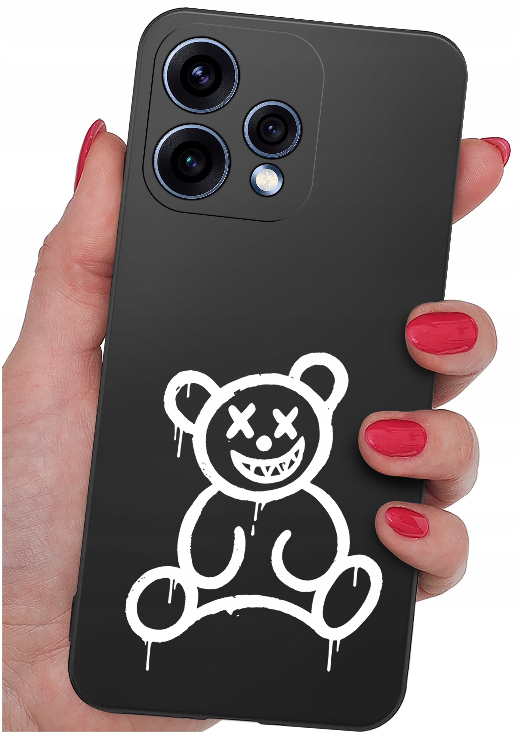 Czarna obudowa telefonu z białym nadrukiem przedstawiającym uśmiechniętego misia z oczami w kształcie krzyżyków. Telefon trzymany jest w dłoni z pomalowanymi na czerwono paznokciami.