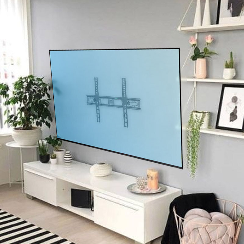 Na ścianie wisi uchwyt do telewizora, otoczony nowoczesnym wnętrzem z roślinami i półkami. W tle znajduje się biały stolik z dekoracjami i roślinami.