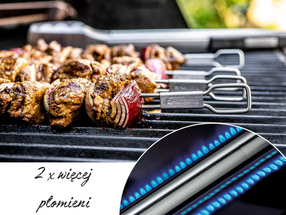 Na grillu znajdują się szaszłyki z mięsa i cebuli, a na metalowych uchwytach widnieje napis \'Broil King\'. W dolnym rogu widoczny jest płomień gazowy oraz tekst \'2 x więcej płomieni\'.