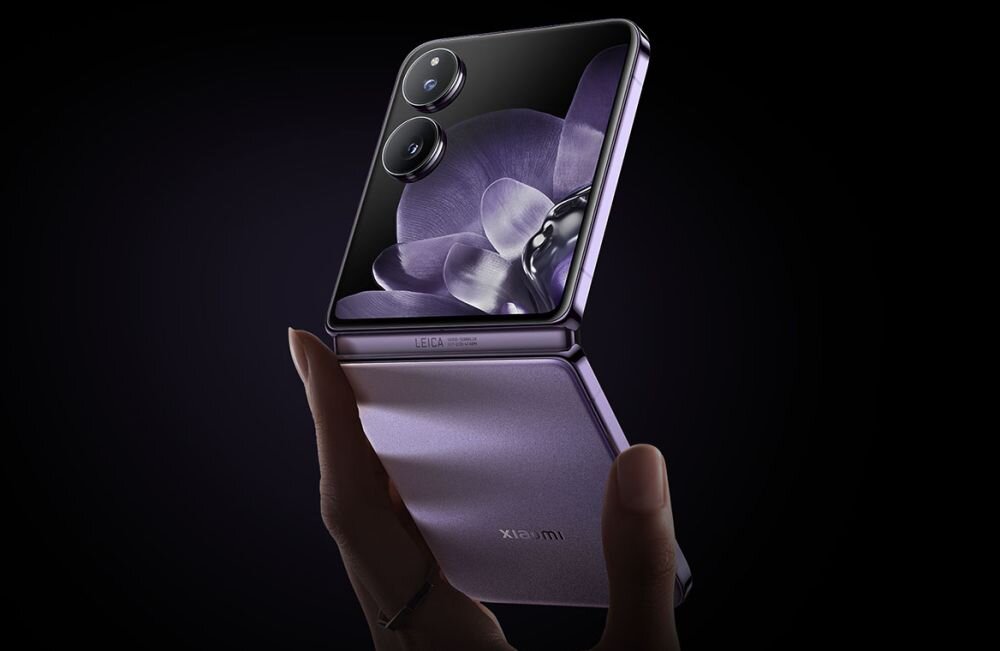 Osoba trzyma składany smartfon z widocznym ekranem, na którym jest kwiatowy motyw. Na obudowie widoczne są dwa obiektywy aparatu oraz napis \'LEICA\'.