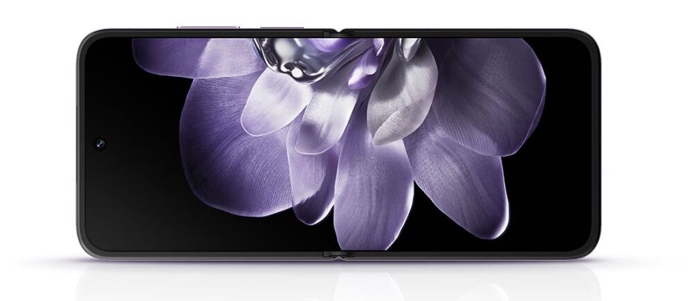 Obraz przedstawia smartfon z dużym, składanym ekranem, na którym widoczny jest fioletowy kwiat. Ekran jest rozłożony, ukazując szczegółowy wzór płatków.