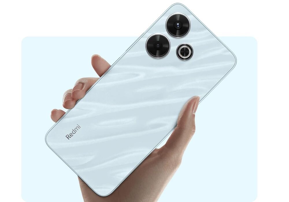 Osoba trzyma smartfon z trzema widocznymi obiektywami aparatu na tylnej obudowie. Na obudowie widoczny jest napis \'Redmi\'.