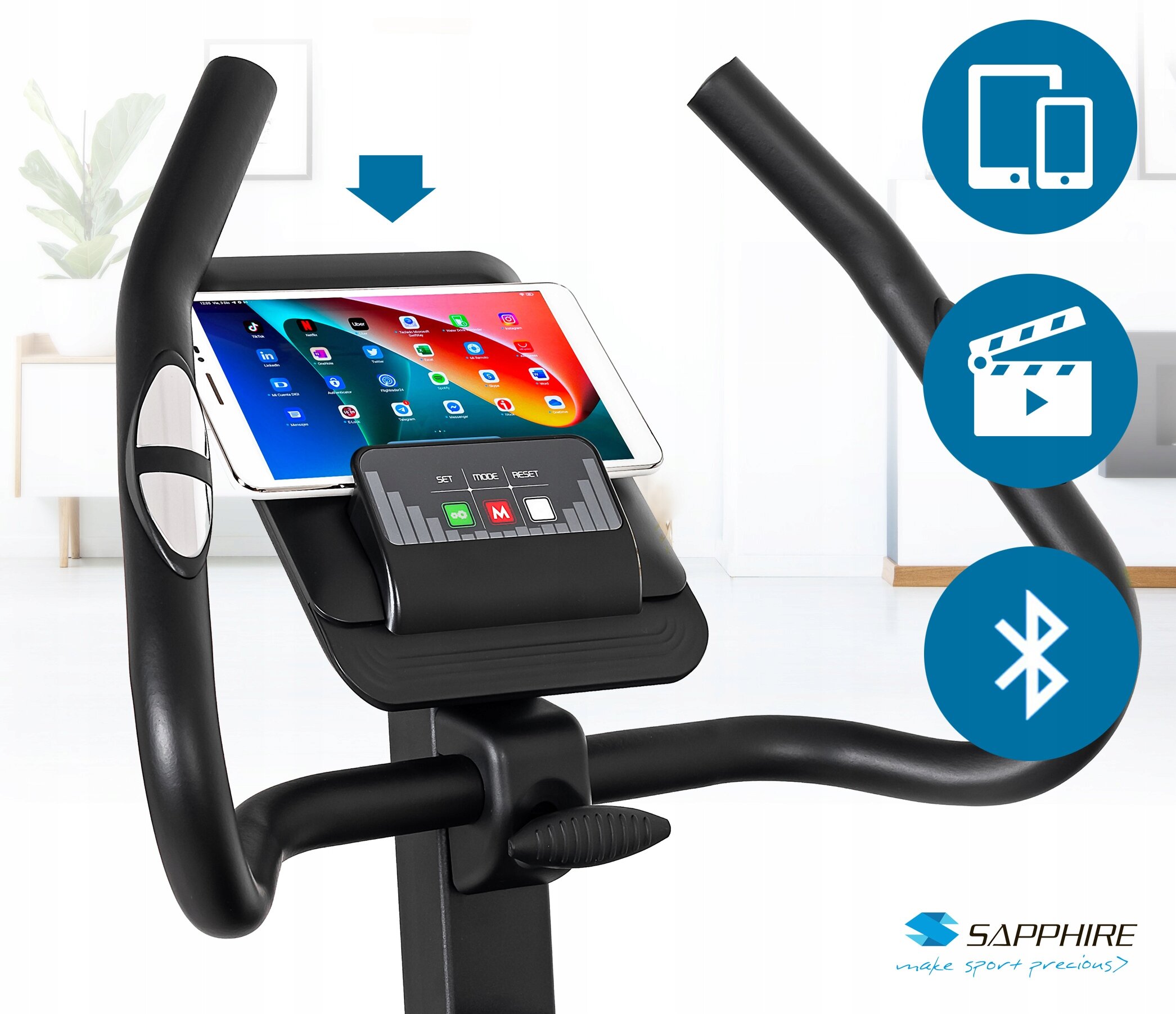 Czarny rower treningowy z uchwytem na tablet, na którym wyświetlony jest ekran z aplikacjami. Obok widoczne są ikony symbolizujące kompatybilność z urządzeniami mobilnymi, odtwarzanie multimediów i Bluetooth, a w prawym dolnym rogu znajduje się logo SAPPHIRE z napisem \'make sport precious\'.