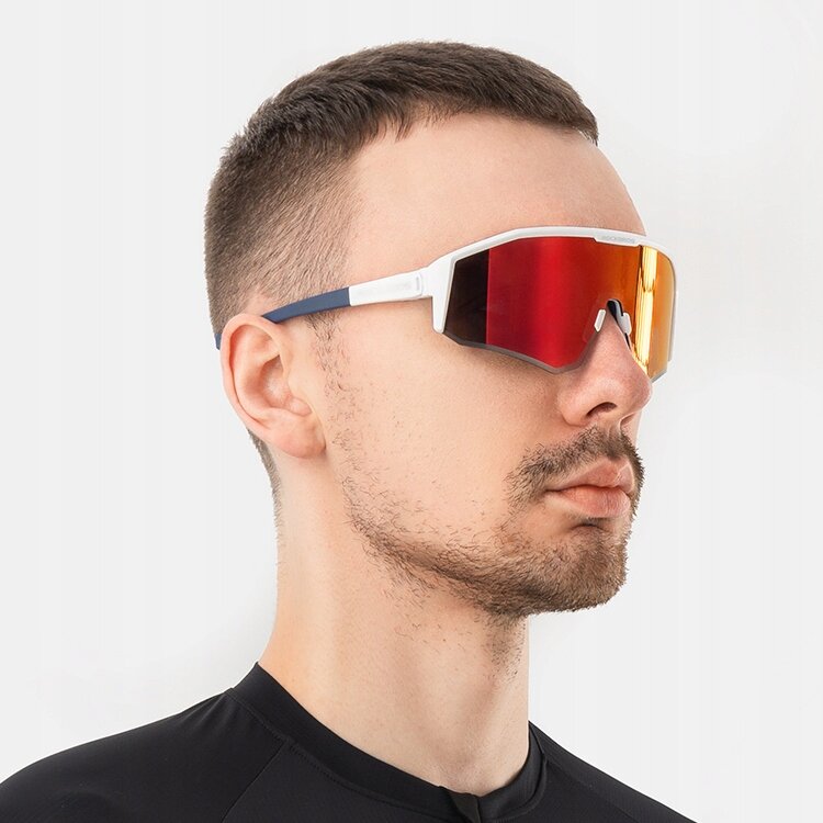 Osoba nosi sportowe okulary przeciwsłoneczne z czerwonymi, lustrzanymi soczewkami i białymi oprawkami. Tło jest jednolite i jasne.