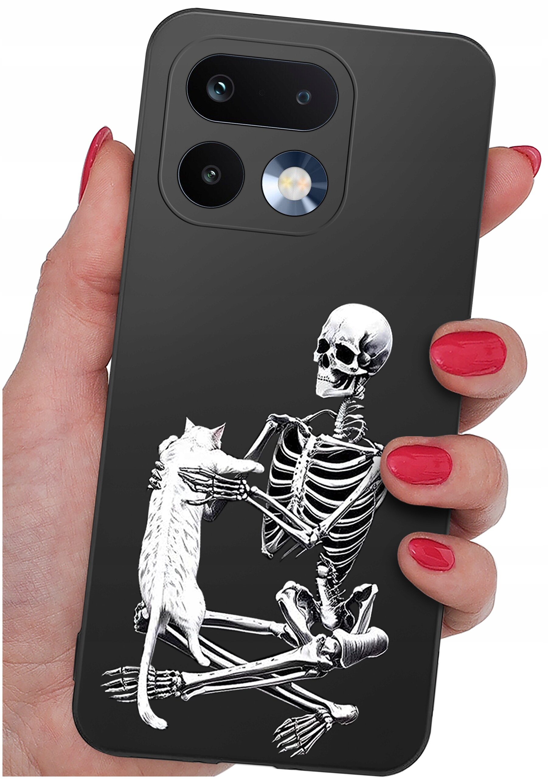 Etui na telefon z grafiką przedstawiającą szkielet trzymający kota. Etui jest trzymane w dłoni z pomalowanymi na czerwono paznokciami.