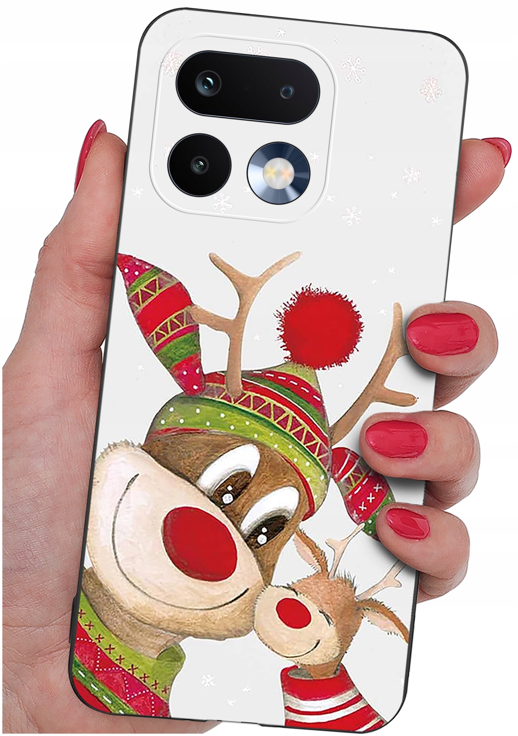 Etui na telefon z motywem renifera w czapce i szaliku, trzymane w dłoni z pomalowanymi na czerwono paznokciami. W tle widoczne są dwa obiektywy aparatu i lampa błyskowa.