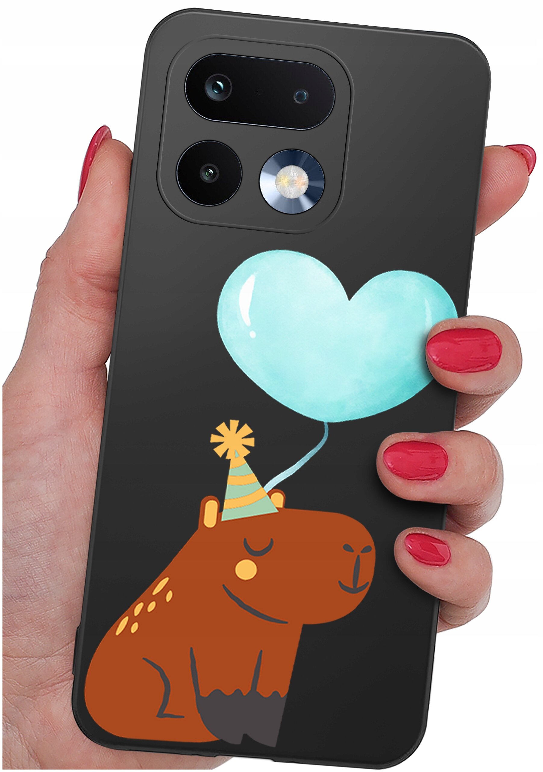 Osoba trzyma czarne etui na telefon z grafiką przedstawiającą brązowe zwierzę w czapeczce urodzinowej i niebieski balon w kształcie serca.