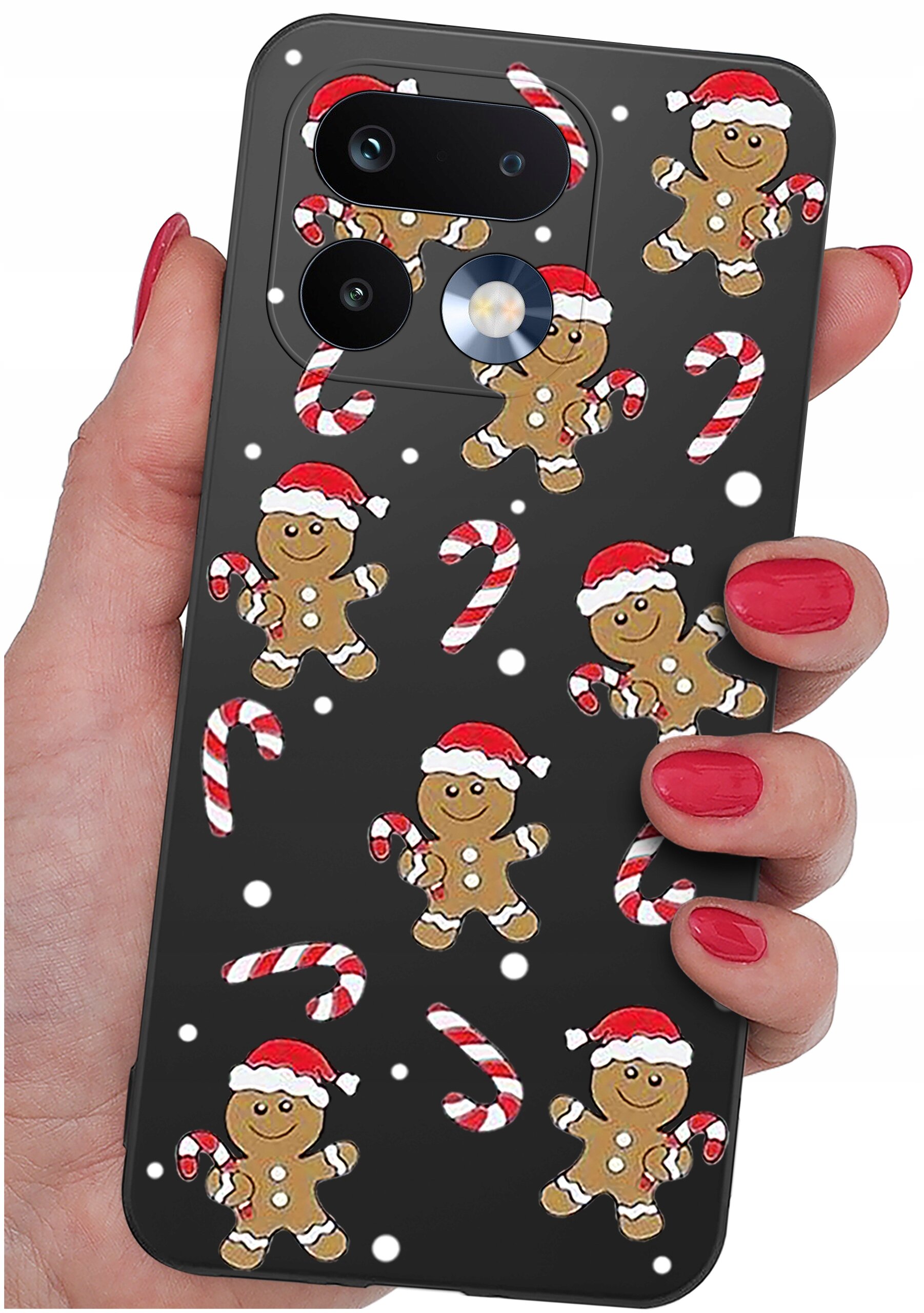 Etui na telefon z motywem świątecznym, przedstawiające piernikowe ludziki w czapkach Mikołaja i cukrowe laski na czarnym tle. Etui trzymane jest w dłoni z pomalowanymi na czerwono paznokciami.