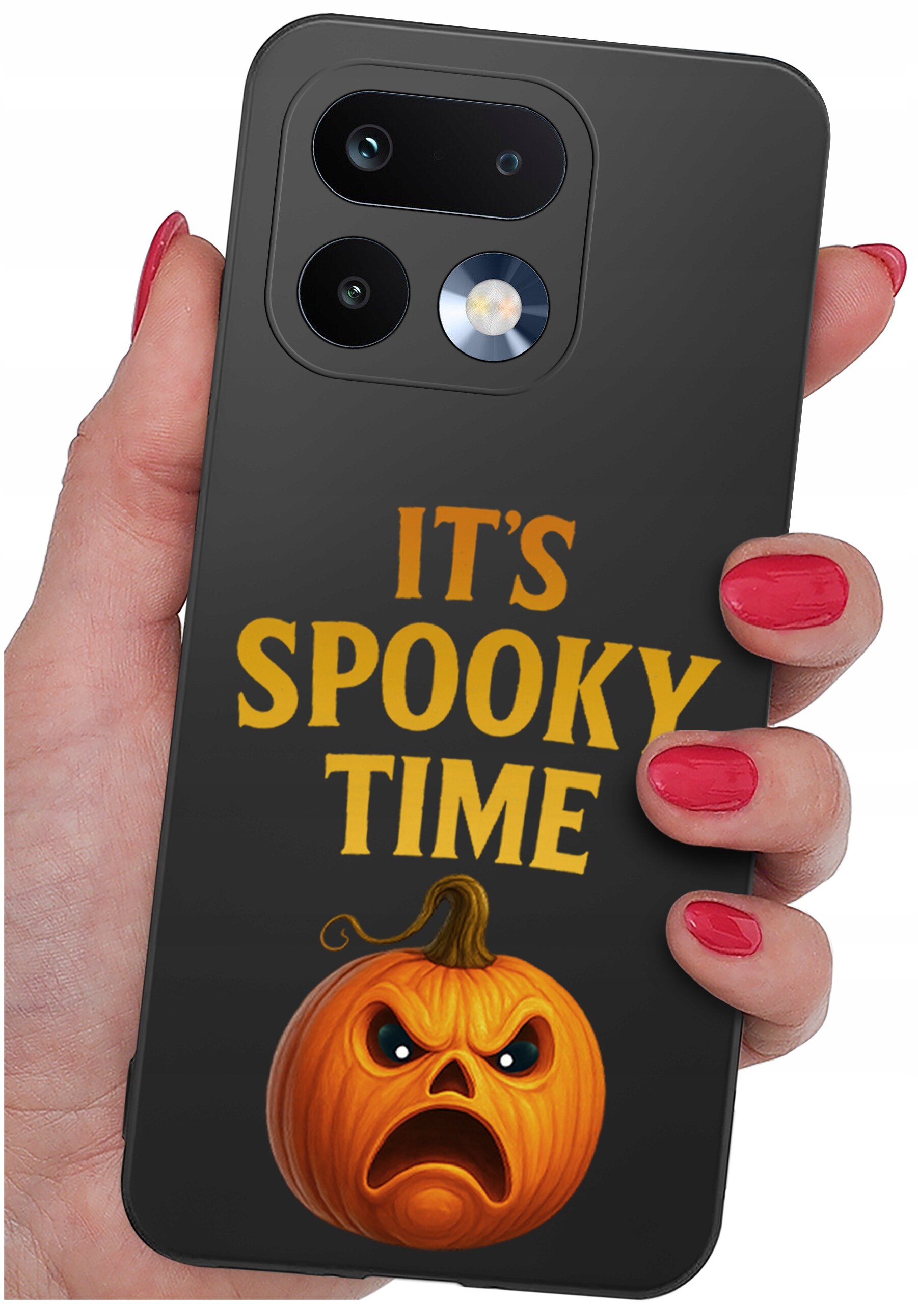 Czarna obudowa telefonu z napisem \'IT\'S SPOOKY TIME\' i grafiką dyni o groźnym wyrazie twarzy. Obudowa jest trzymana w dłoni z pomalowanymi na czerwono paznokciami.