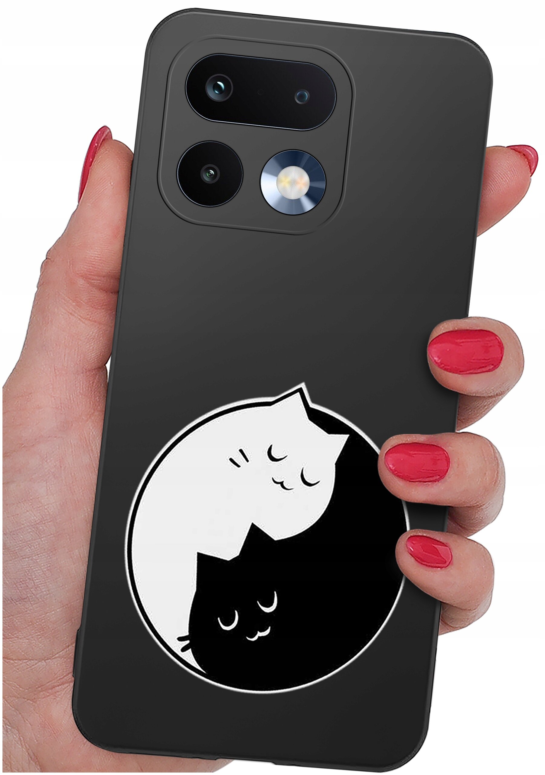 Czarna obudowa telefonu z nadrukiem dwóch kotów w stylu yin-yang, trzymana w dłoni z pomalowanymi na czerwono paznokciami. Obok aparatu widoczne są dwa obiektywy i lampa błyskowa.
