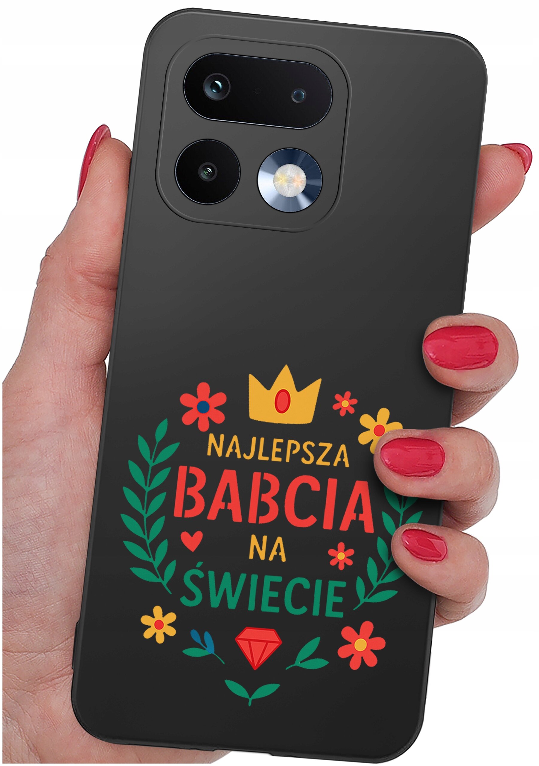 Czarna obudowa telefonu z kolorowym napisem \'NAJLEPSZA BABCIA NA ŚWIECIE\' oraz ozdobami w postaci kwiatów i korony. Obudowa jest trzymana w dłoni z pomalowanymi na czerwono paznokciami.