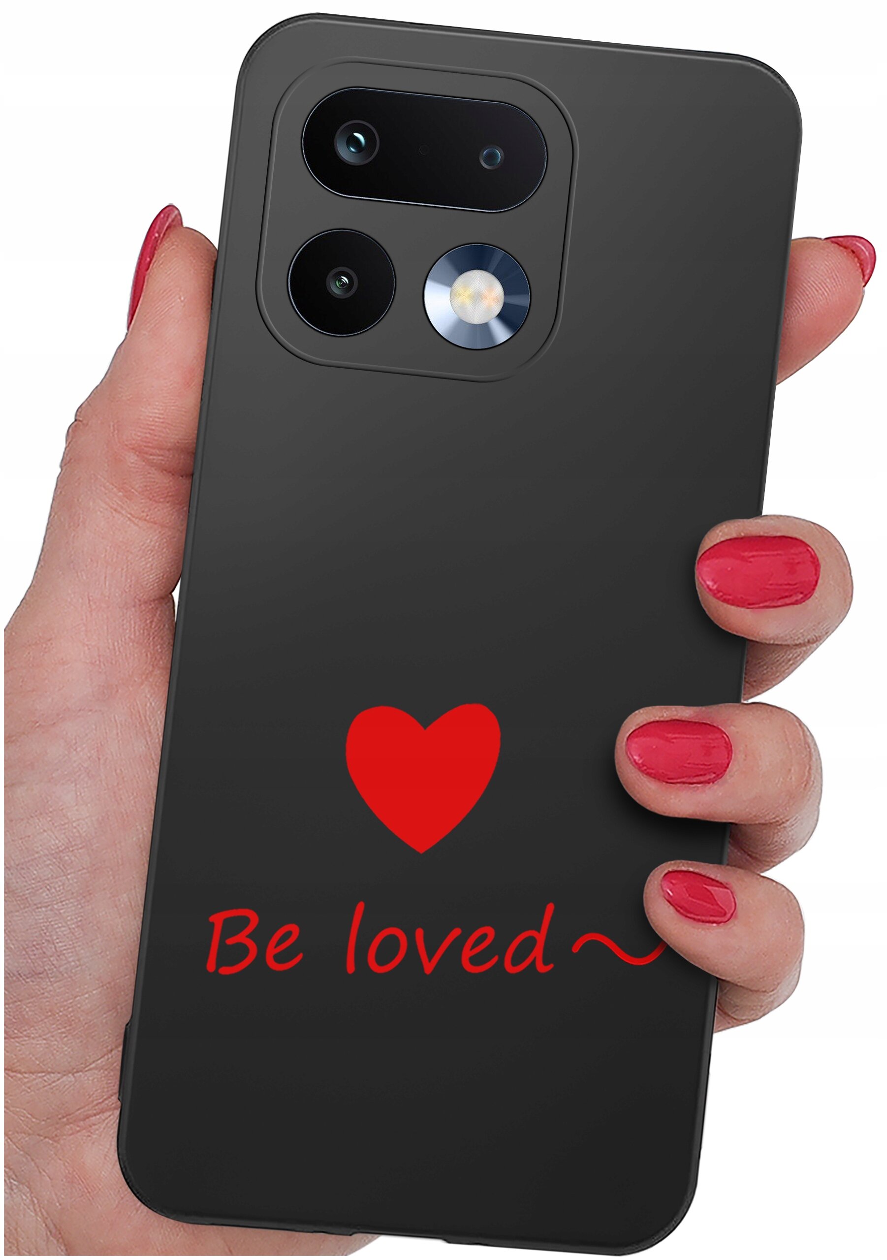 Czarna obudowa telefonu z czerwonym sercem i napisem \'Be loved ~\'. Obudowa trzymana jest w dłoni z pomalowanymi na czerwono paznokciami.