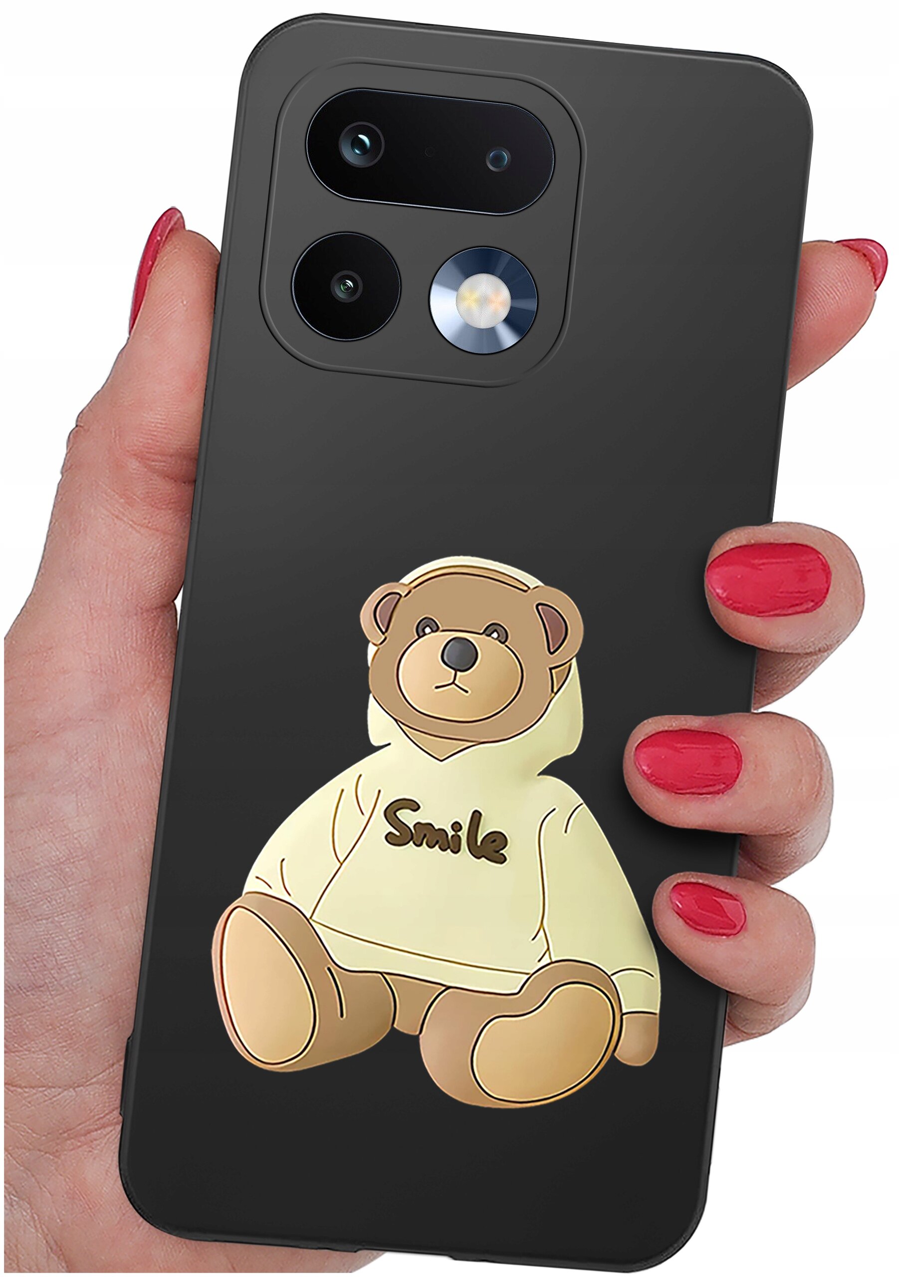 Czarna obudowa telefonu z nadrukiem misia w bluzie z napisem \'Smile\'. Obudowa jest trzymana w dłoni z pomalowanymi na czerwono paznokciami.