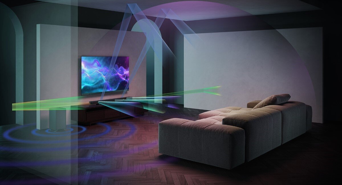 W salonie znajduje się telewizor z wyświetlanym kolorowym obrazem oraz soundbar umieszczony pod nim. Wokół soundbara widoczne są kolorowe linie symbolizujące dźwięk przestrzenny.