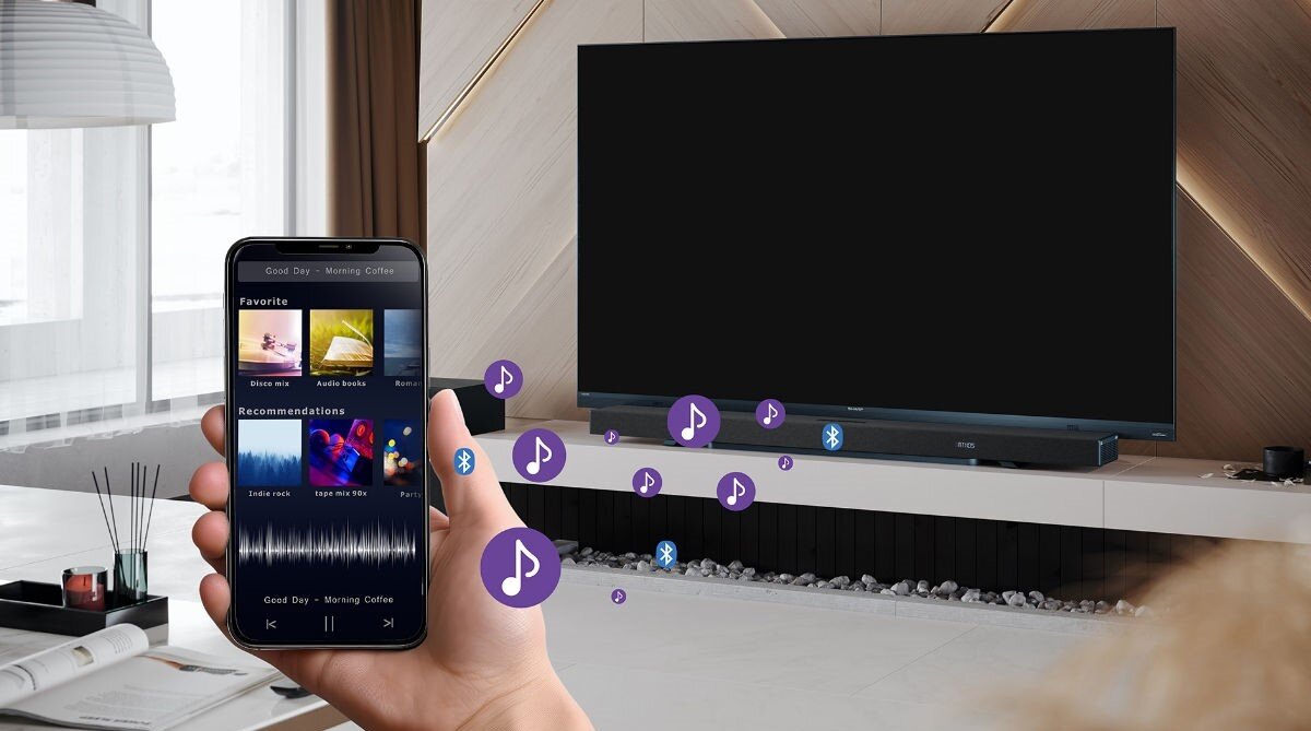 Osoba trzyma smartfon z aplikacją muzyczną, na ekranie widać listę utworów i rekomendacje. W tle znajduje się duży telewizor z soundbarem, a wokół unoszą się ikony nutek i symbol Bluetooth.