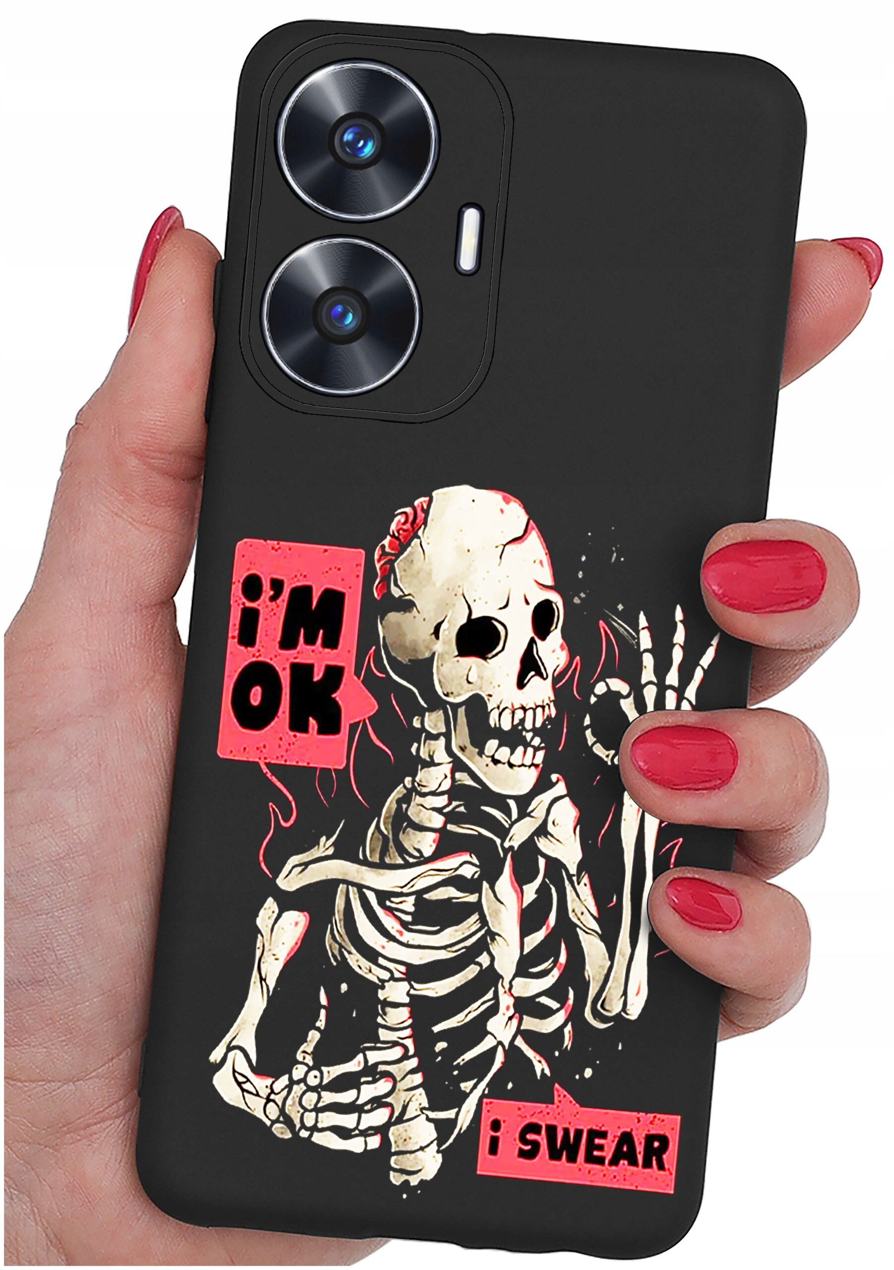 Czarna obudowa telefonu z grafiką szkieletu i napisami \'i\'m OK\' oraz \'i SWEAR\'. Obudowa trzymana jest w dłoni z pomalowanymi na czerwono paznokciami.