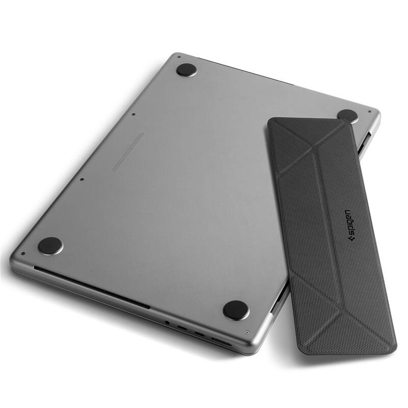 Na obrazie widoczny jest laptop leżący na płaskiej powierzchni, a obok niego czarny stojak z logo \'Spigen\'.