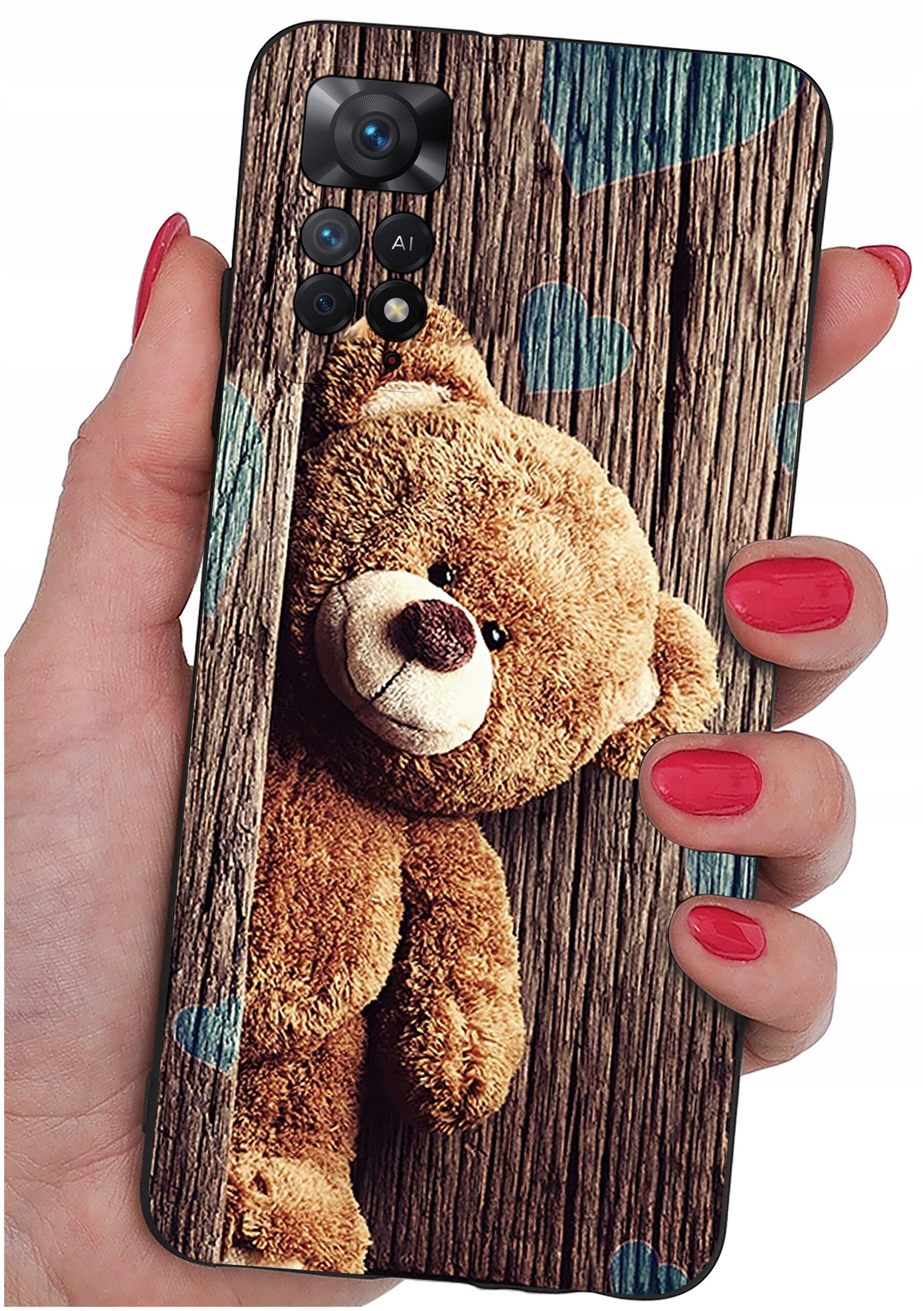 Etui na telefon z nadrukiem misia na tle drewnianych desek, trzymane w dłoni z pomalowanymi na czerwono paznokciami. Na etui widoczne są również niebieskie serca.