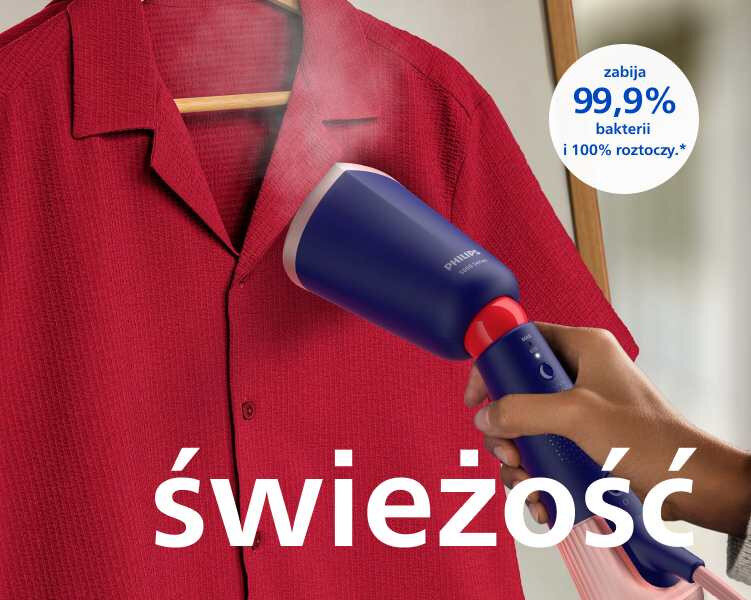 Osoba używa niebieskiej parownicy do ubrań na czerwonej koszuli wiszącej na wieszaku. Na obrazie widoczny jest tekst: \'świeżość\' oraz \'zabija 99,9% bakterii i 100% roztoczy.\'