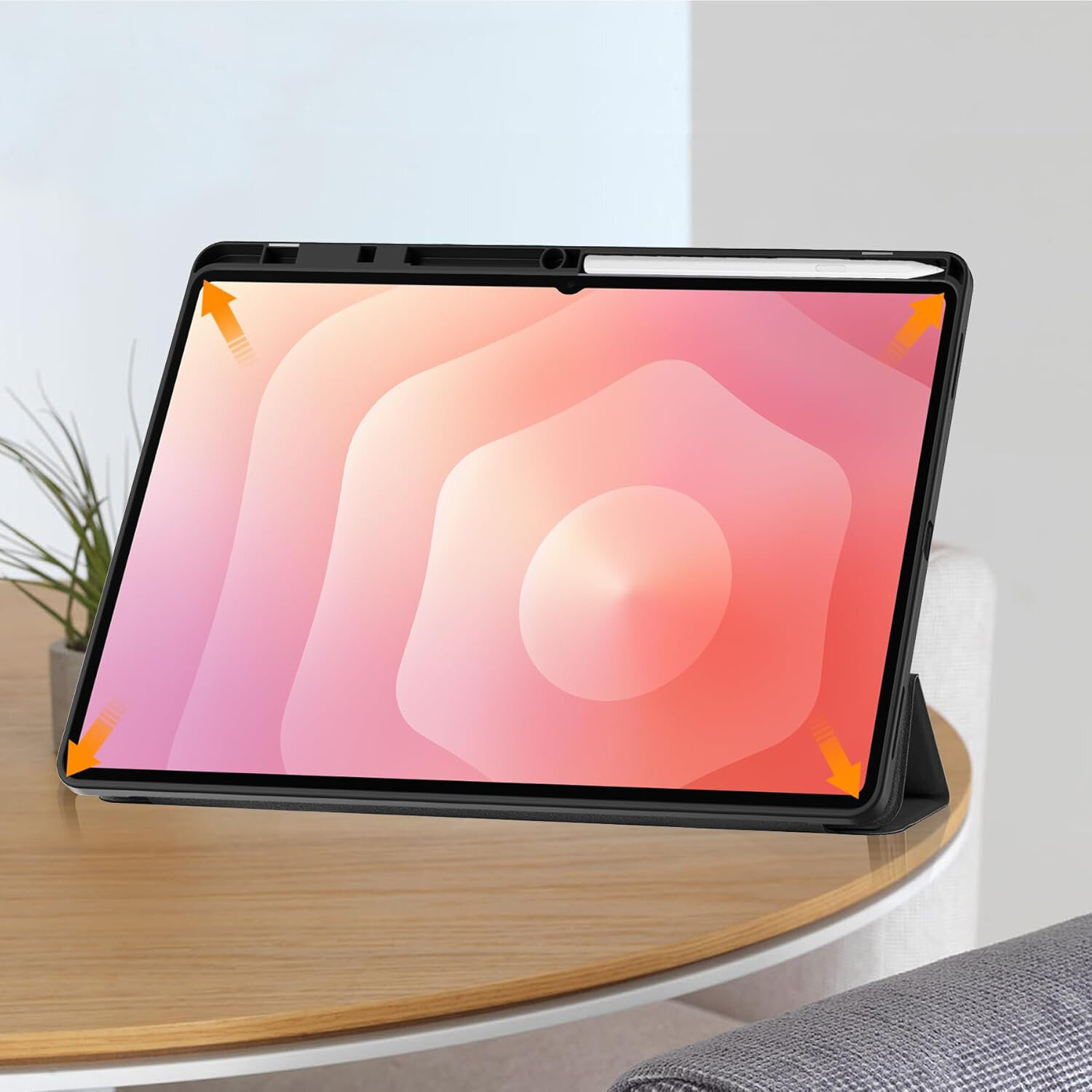 Tablet w etui z klapką stoi na drewnianym stole, z widocznym miejscem na rysik. Na ekranie wyświetlany jest gradientowy wzór w odcieniach różu i pomarańczu.