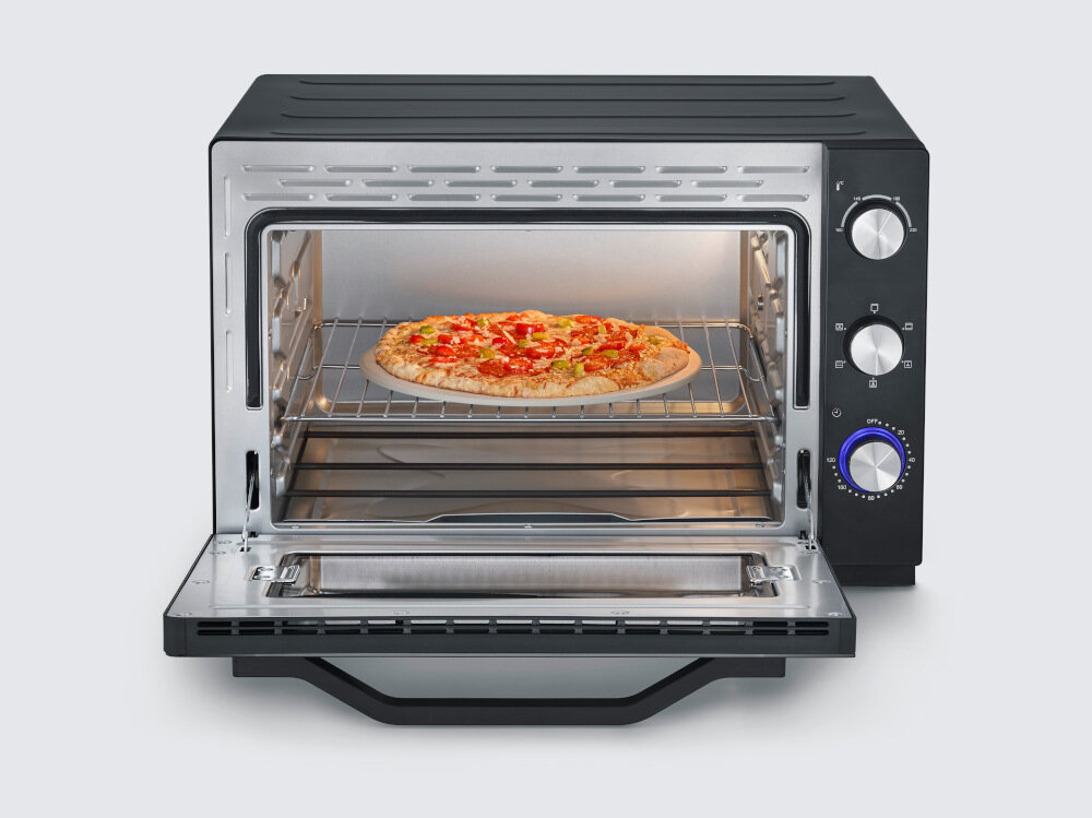 Otwarty mini piekarnik z pizzą na ruszcie. Piekarnik ma czarną obudowę i trzy pokrętła sterujące po prawej stronie.