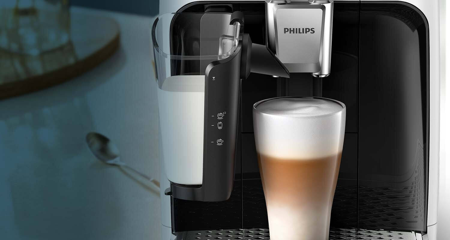 Ekspres do kawy z logo PHILIPS przygotowuje kawę z mleczną pianką w wysokiej szklance. Obok ekspresu widoczny jest pojemnik na mleko z oznaczeniami funkcji.