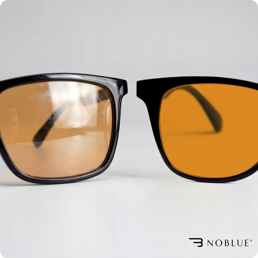 Na obrazie widoczne są okulary z pomarańczowymi soczewkami i czarnymi oprawkami. W prawym dolnym rogu znajduje się logo \'NOBLUE\'.