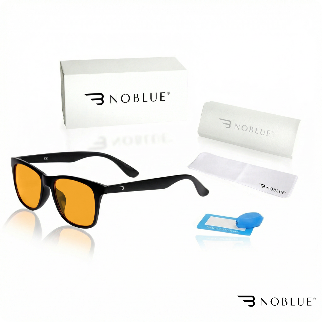 Na obrazie widoczne są okulary z pomarańczowymi soczewkami, czarnymi oprawkami oraz akcesoria takie jak etui, ściereczka i niebieski tester światła. Logo \'NOBLUE\' znajduje się na pudełku, etui, ściereczce oraz w prawym dolnym rogu obrazu.