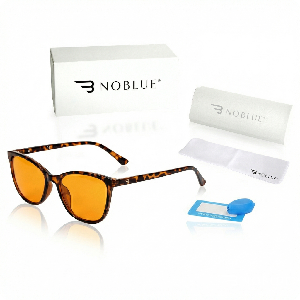 Na obrazie widoczne są okulary z pomarańczowymi soczewkami i oprawkami w stylu panterki, obok pudełko z logo \'NOBLUE\', etui, ściereczka oraz niebieski tester światła. Wszystkie elementy są ułożone na białym tle.