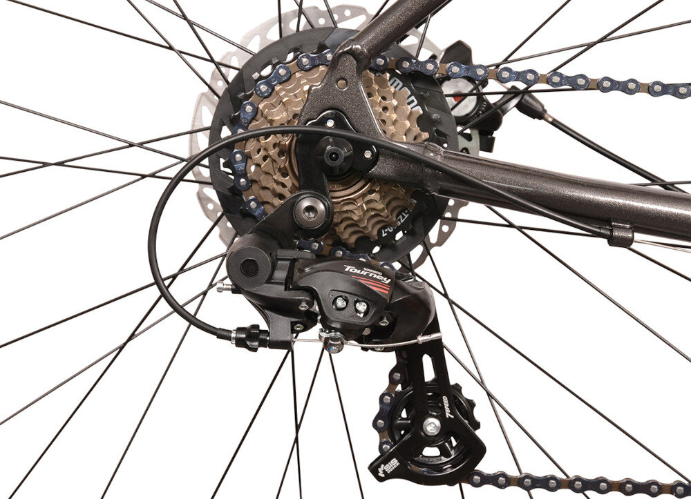 Zdjęcie przedstawia mechanizm tylnej przerzutki rowerowej z widocznym napisem \'Tourney\'. W tle widać zębatki i część łańcucha rowerowego.