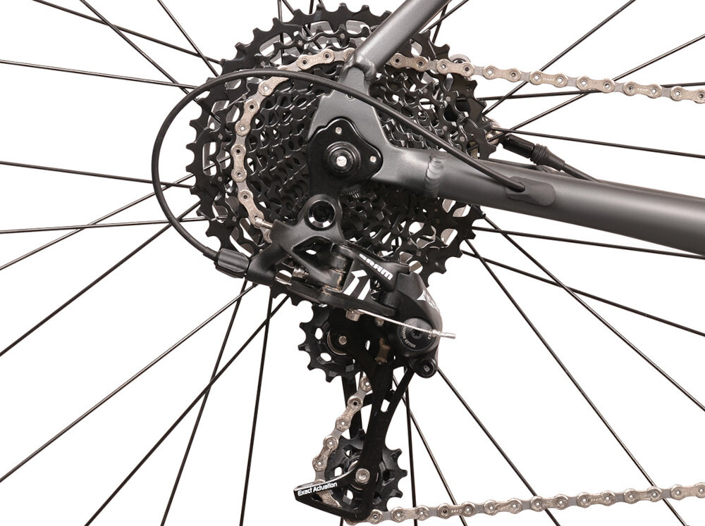 Zdjęcie przedstawia tylną przerzutkę roweru z widocznym mechanizmem zębatek i łańcuchem. Elementy są w ciemnym kolorze, a rama roweru jest ciemnoszara.