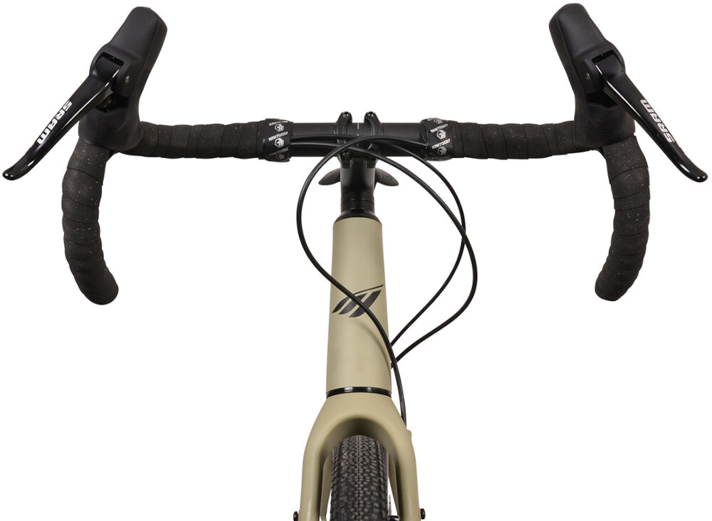 Zdjęcie przedstawia kierownicę roweru gravel w kolorze piaskowym z czarnymi uchwytami i dźwigniami hamulcowymi z napisem \'Sram\'. Na ramie widoczne jest logo w formie stylizowanej litery \'M\'.