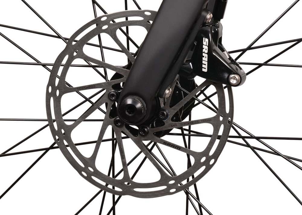 Zbliżenie na tarczę hamulcową roweru z widocznym napisem \'SRAM\' na zacisku hamulca. Tarcza jest metalowa z otworami, a wokół niej znajdują się szprychy koła.