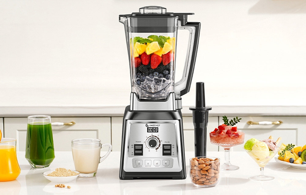 Na blacie kuchennym stoi blender kielichowy z logo AMZCHEF, wypełniony owocami. Obok znajdują się różne napoje i przekąski, w tym zielony sok, kawa i miseczki z orzechami.