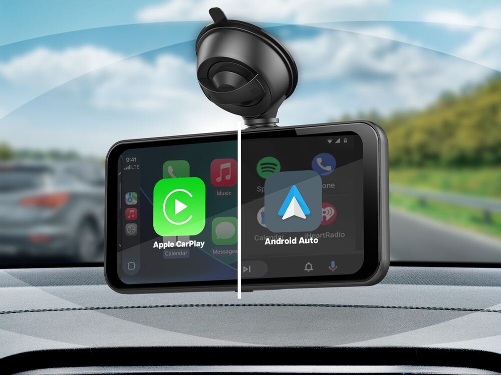 Na obrazie widoczny jest samochodowy tablet multimedialny zamontowany na desce rozdzielczej, z wyświetlonymi ikonami Apple CarPlay i Android Auto. W tle widać rozmyty krajobraz drogi i samochodów.