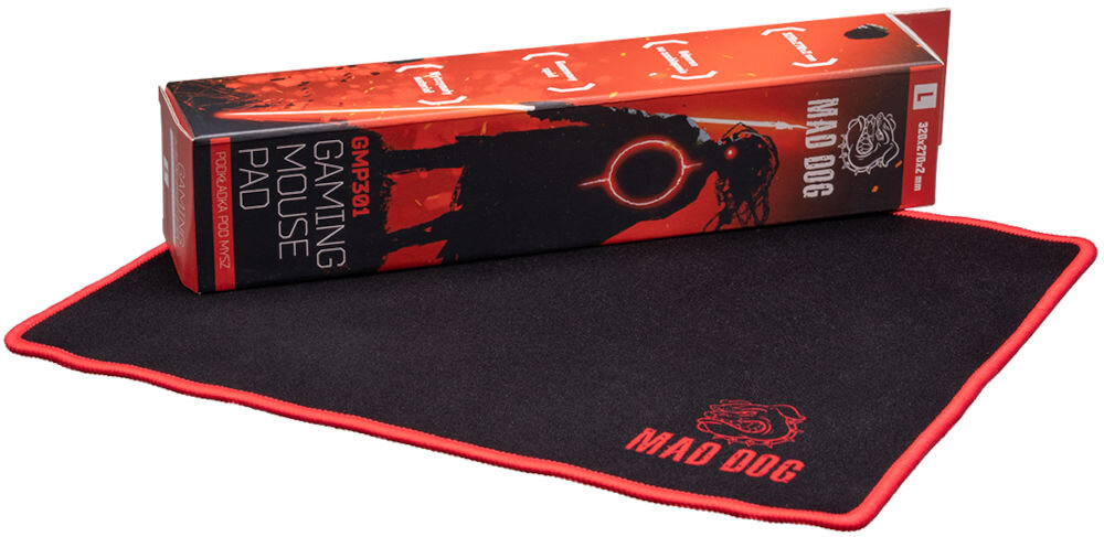 Podkładka MAD DOG GMP301 Widok na czarną podkładkę Mad Dog GMP301 z opakowaniem (pudełkiem) leżącym na niej. Pudełko jest długie, czerwono-czarne, z grafiką sylwetki postaci i logo, a także widocznym modelem GMP301 oraz wymiarami 320x270x2 mm.