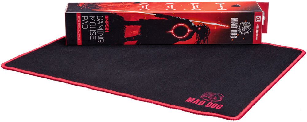 Podkładka MAD DOG GMP501 Widok na czarną podkładkę Mad Dog GMP501 z opakowaniem (pudełkiem) leżącym na niej. Pudełko jest długie, czerwono-czarne, z grafiką sylwetki postaci i logo, a także widocznym modelem GMP501 oraz wymiarami 320x270x2 mm.