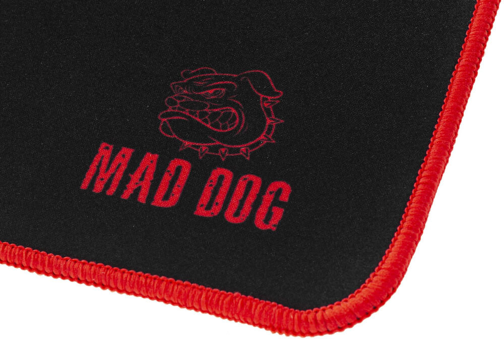 Podkładka MAD DOG GMP701 Widok perspektywiczny z bliska na czarną podkładkę Mad Dog GMP701 z wyraźnym czerwonym obszyciem. Podkładka jest pusta. W prawym dolnym rogu widoczne czerwone logo Mad Dog.