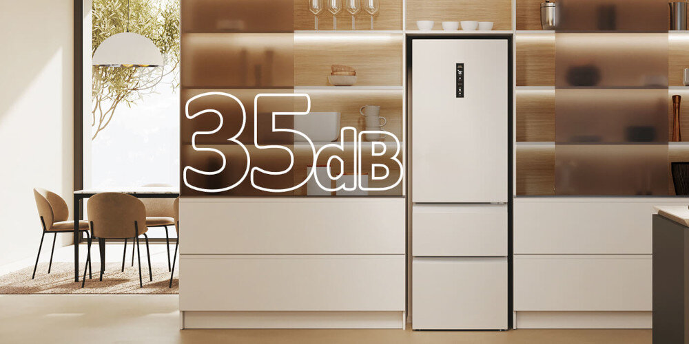Wnętrze nowoczesnej kuchni z białą lodówką w zabudowie, obok której widoczny jest duży napis \'35 dB\'.