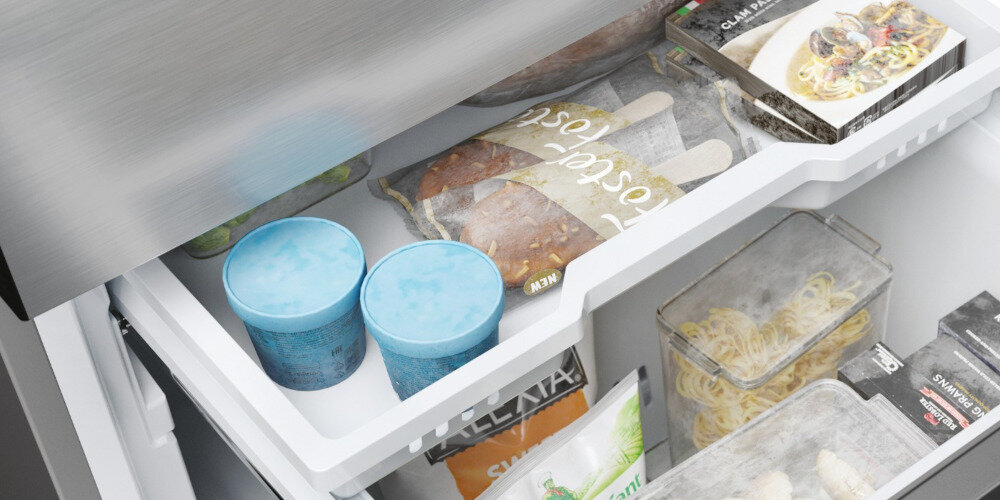 Wnętrze zamrażarki z widocznymi produktami spożywczymi, w tym dwa niebieskie pojemniki, opakowania z mrożonymi produktami oraz przezroczyste pojemniki z makaronem. Na opakowaniach widoczne są napisy, ale nie są one w pełni czytelne.