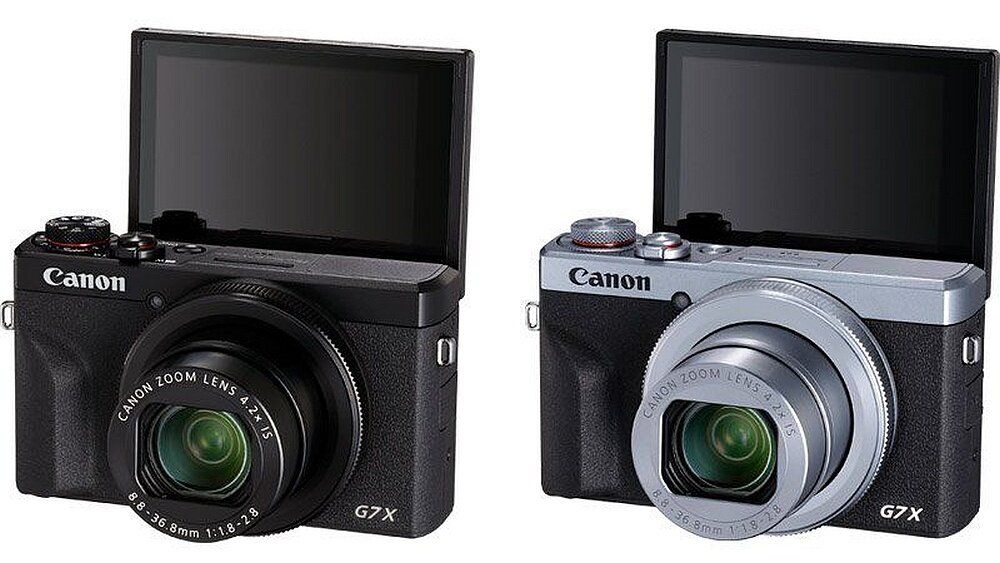 Dwa aparaty fotograficzne z wysuniętymi obiektywami i odchylonymi ekranami. Na obiektywach widoczny jest napis \'CANON ZOOM LENS 4.2X\'.
