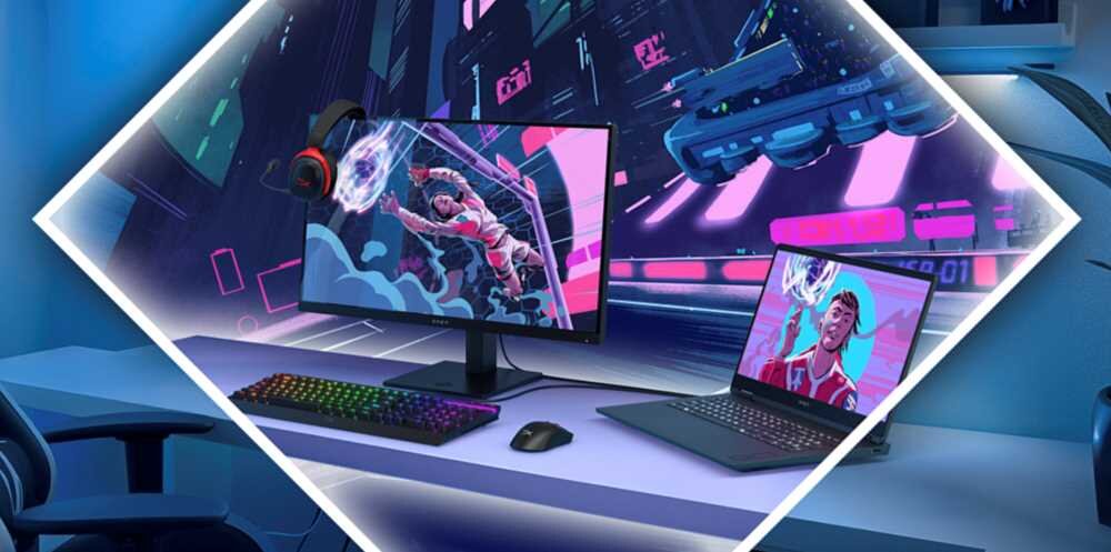 Na biurku znajduje się monitor z kolorową grafiką przedstawiającą postać w dynamicznej pozie oraz laptop z podobnym obrazem na ekranie. Obok monitora leży klawiatura z podświetleniem RGB i myszka, a na monitorze wisi para słuchawek.