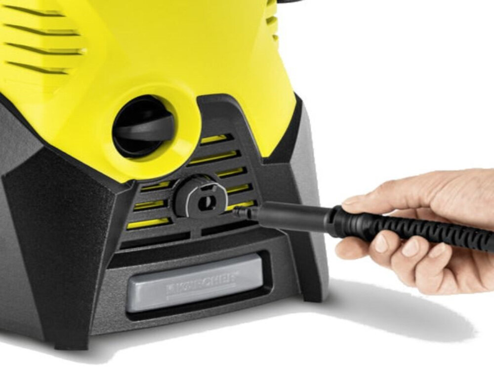 Osoba trzymająca wąż podłącza go do żółto-czarnej myjki ciśnieniowej. Na urządzeniu widoczne jest logo \'KARCHER\'.