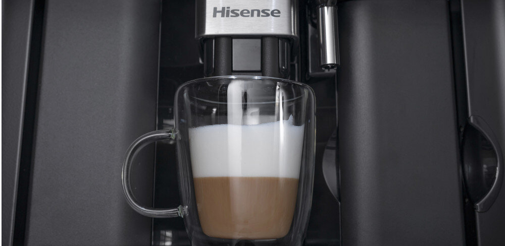 Ekspres do kawy z logo Hisense przygotowuje kawę z mleczną pianką w szklance. Urządzenie ma ciemny kolor i nowoczesny design.