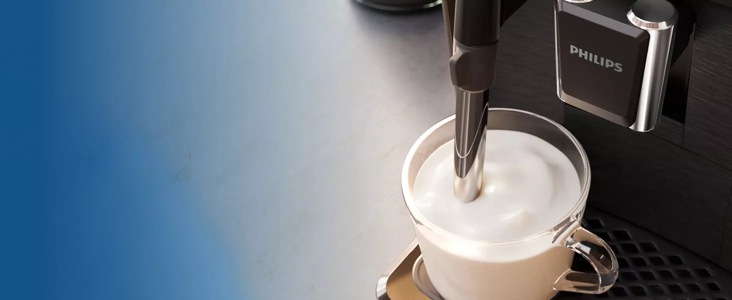 Na obrazie widoczny jest ekspres do kawy z logo PHILIPS, przygotowujący mleczną piankę w szklance. Ekspres znajduje się na metalowej powierzchni.