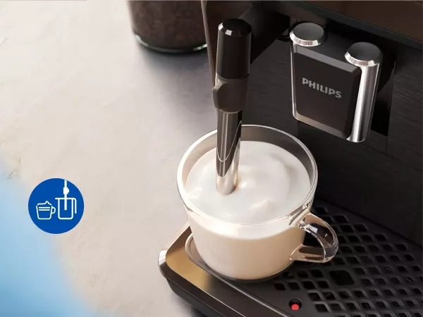 Na obrazie widoczny jest ekspres do kawy z logo PHILIPS, przygotowujący mleczną piankę w szklance. Obok znajduje się niebieska ikona z symbolem filiżanki i spieniacza do mleka.