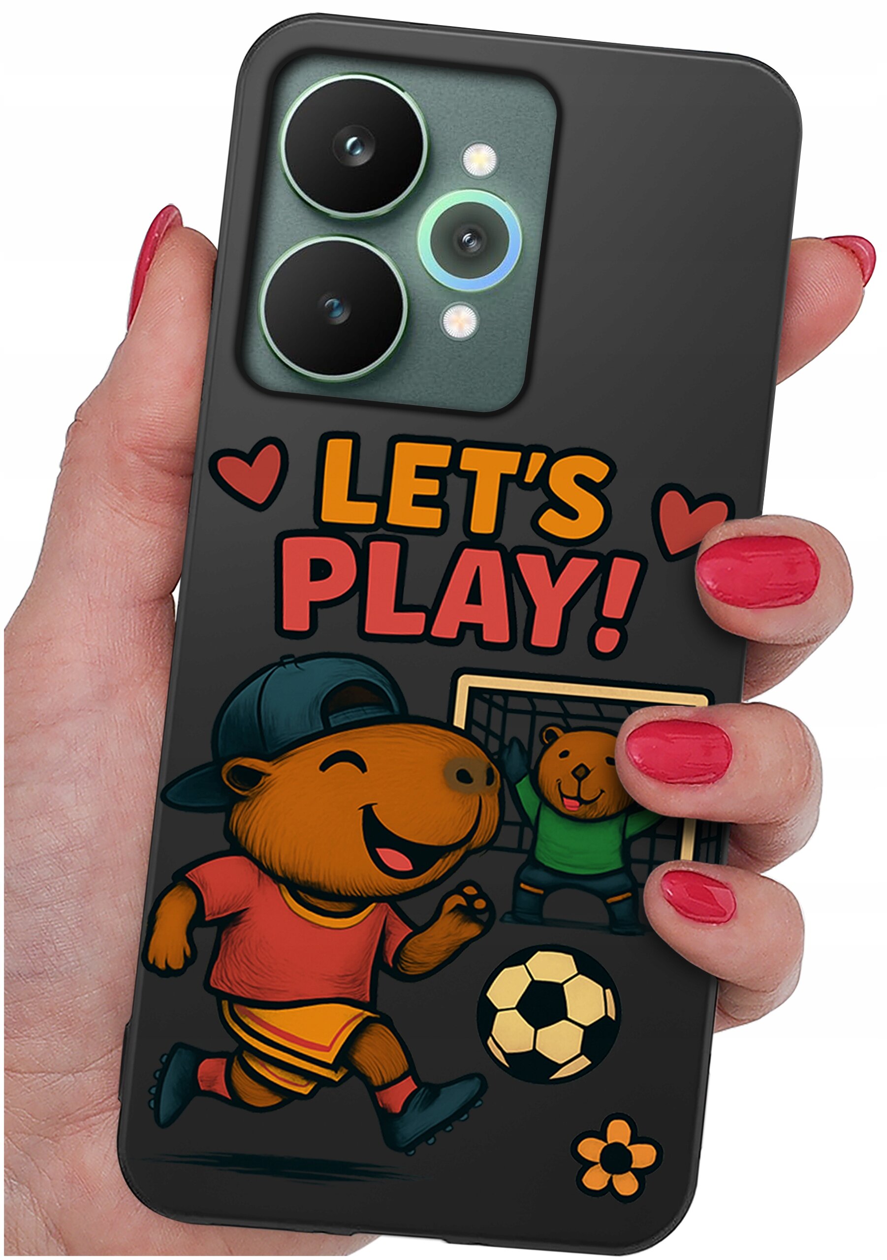 Etui na telefon z grafiką przedstawiającą uśmiechnięte zwierzątko w czapce i stroju sportowym, piłkę oraz napis \'LET\'S PLAY!\' otoczony serduszkami. Etui trzymane jest w dłoni z pomalowanymi na czerwono paznokciami.